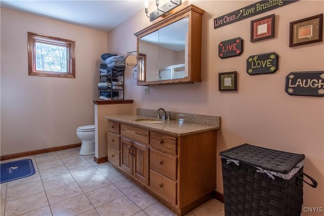 bathroom featuring baseboards, vanity, toilet, and tile patterned floors