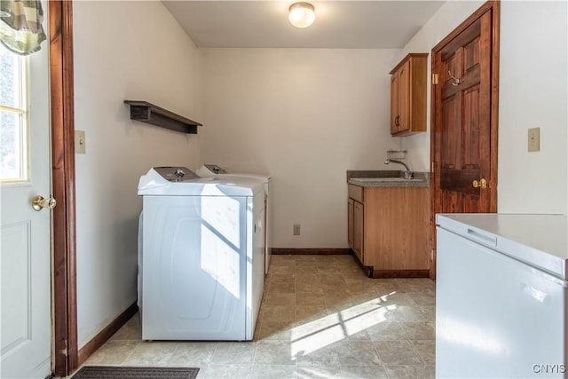 laundry area featuring independent washer and dryer, a sink, cabinet space, and baseboards