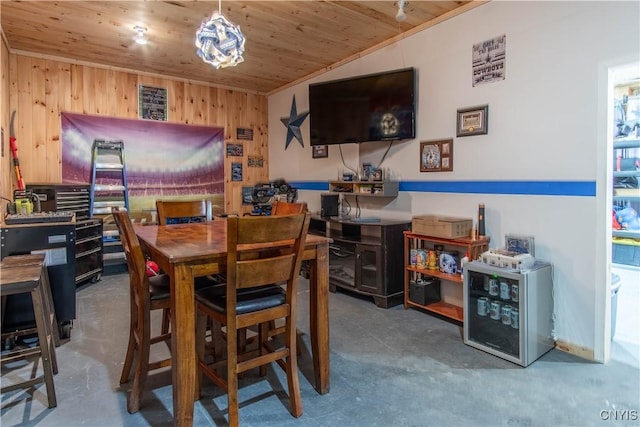 dining space with wooden ceiling, concrete floors, and wood walls