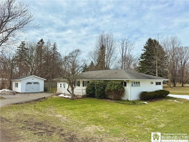 ranch-style house featuring driveway, a detached garage, a front lawn, and an outbuilding