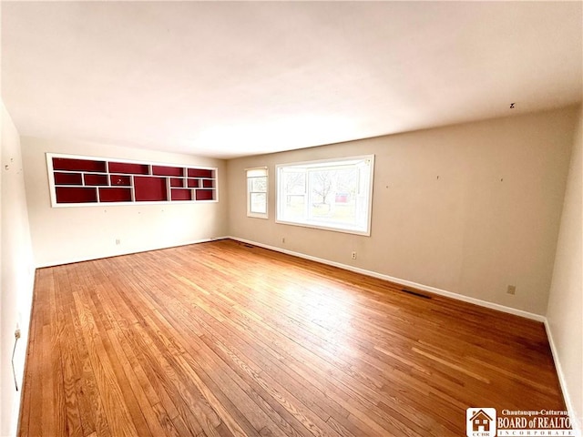 spare room with visible vents, baseboards, and wood finished floors