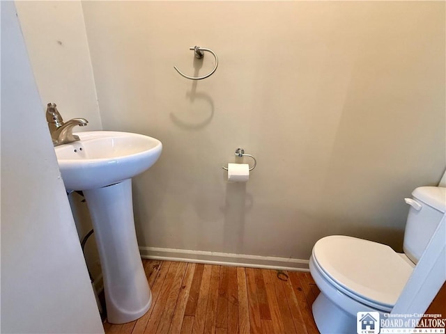 bathroom featuring baseboards, a sink, toilet, and wood finished floors