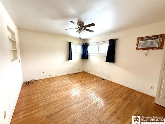 unfurnished room with visible vents, a wall mounted AC, light wood-style floors, ceiling fan, and baseboards