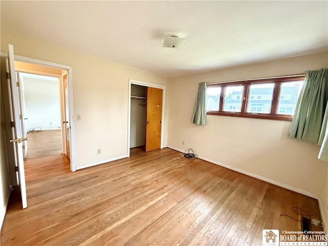 unfurnished bedroom with light wood-style flooring, baseboards, and a closet