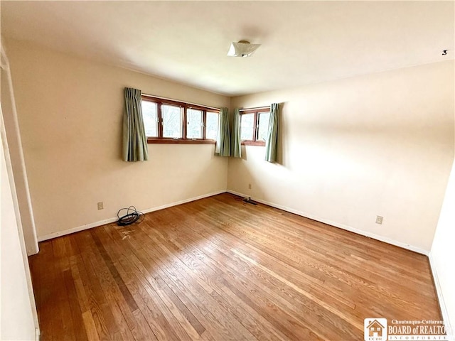 spare room featuring hardwood / wood-style flooring and baseboards