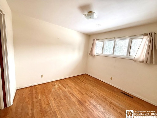 spare room with baseboards, visible vents, and light wood-style floors