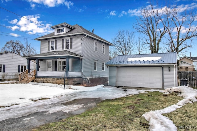 traditional style home with a porch, metal roof, fence, a garage, and an outdoor structure