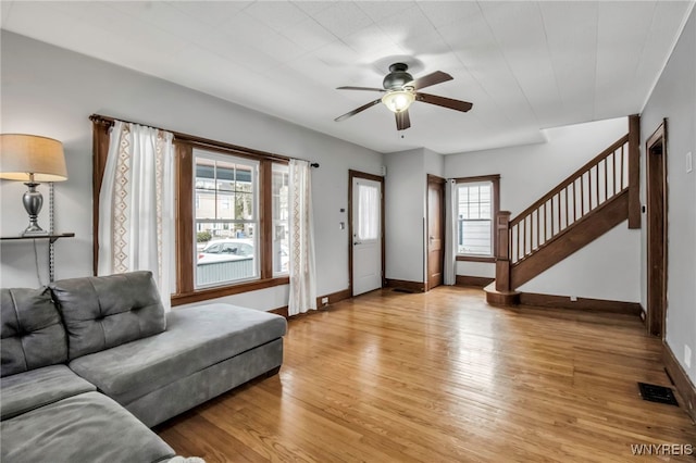 living area with ceiling fan, visible vents, baseboards, stairway, and light wood-type flooring