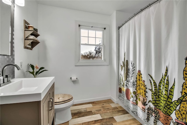 bathroom with curtained shower, toilet, vanity, wood finished floors, and baseboards