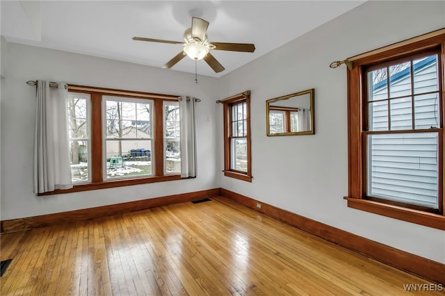 unfurnished room featuring light wood finished floors, baseboards, visible vents, and a ceiling fan