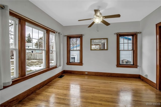 empty room with light wood-type flooring, visible vents, ceiling fan, and baseboards