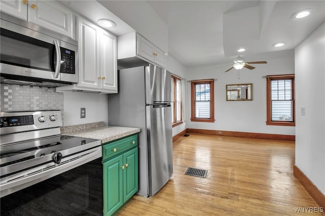 kitchen featuring light wood-style flooring, white cabinetry, baseboards, appliances with stainless steel finishes, and tasteful backsplash