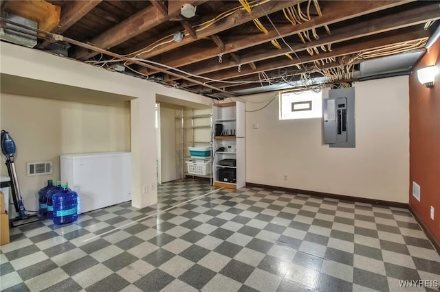 below grade area with fridge, baseboards, electric panel, and visible vents