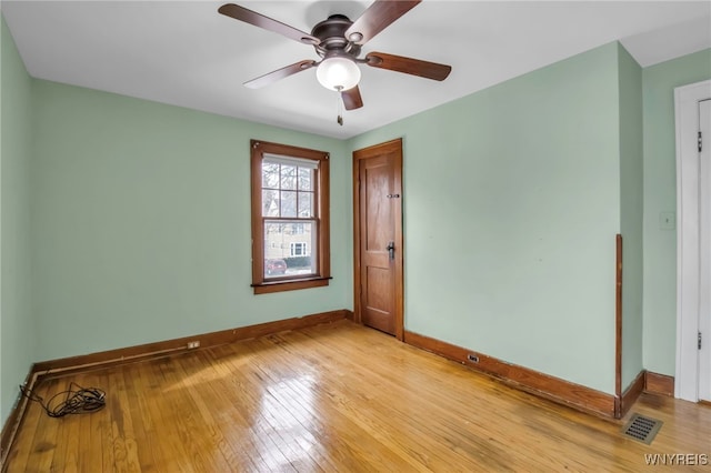 spare room with baseboards, a ceiling fan, visible vents, and light wood-style floors