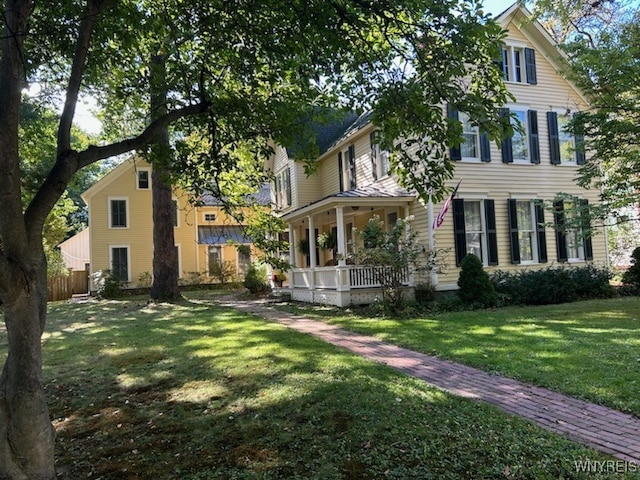 view of front of home featuring covered porch, a front lawn, and fence