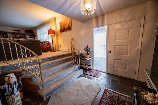 entrance foyer with a baseboard heating unit, stairway, stone tile flooring, and a notable chandelier