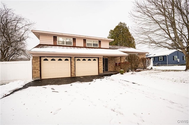 traditional home with aphalt driveway, brick siding, fence, and an attached garage