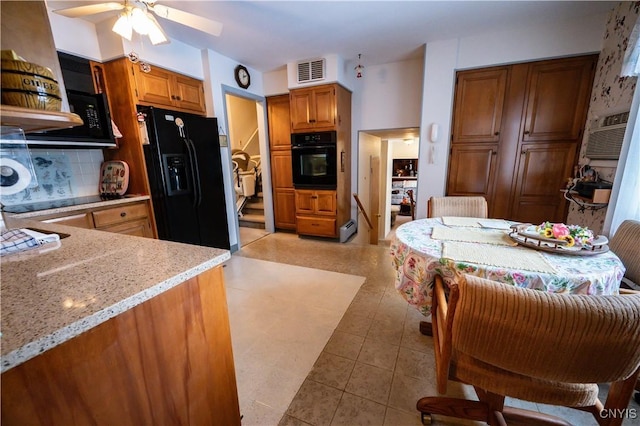 kitchen featuring visible vents, decorative backsplash, brown cabinetry, light stone countertops, and black appliances