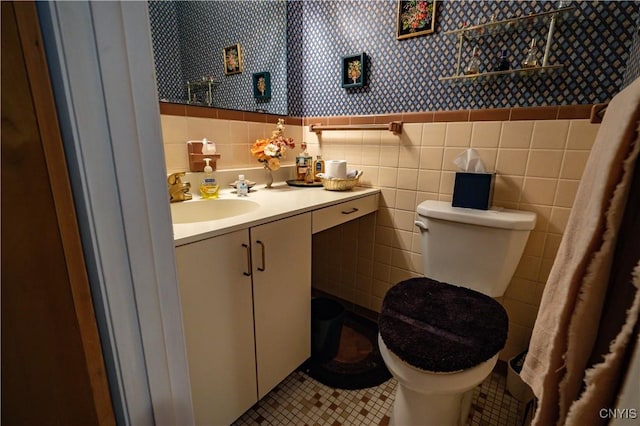 bathroom with a wainscoted wall, tile walls, toilet, tile patterned flooring, and wallpapered walls