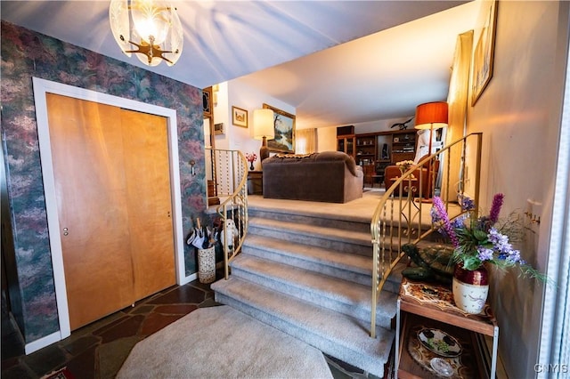 entryway featuring stairs, wallpapered walls, baseboards, and a notable chandelier