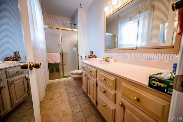 bathroom featuring toilet, a shower stall, vanity, and tile patterned floors