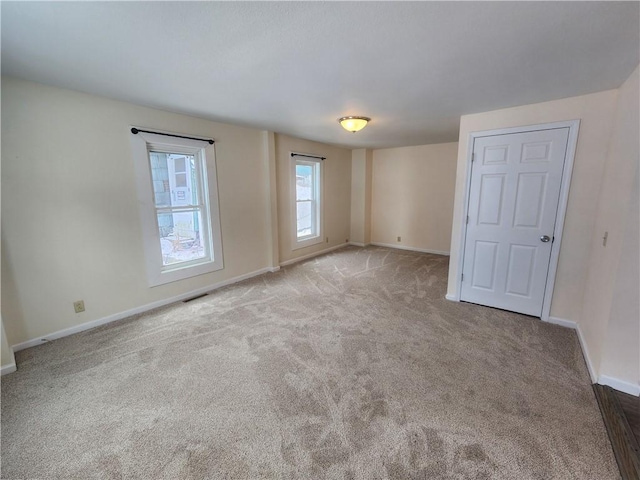 carpeted spare room featuring visible vents and baseboards