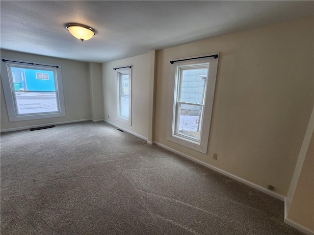 carpeted empty room with visible vents and baseboards