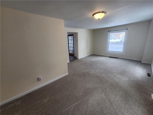 carpeted spare room featuring visible vents and baseboards