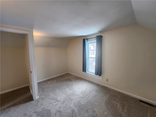 additional living space featuring carpet floors, baseboards, visible vents, and vaulted ceiling