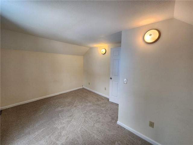 carpeted spare room featuring vaulted ceiling and baseboards