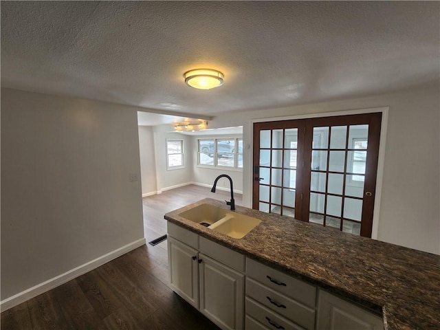 kitchen featuring dark wood-style flooring, white cabinets, a sink, and a textured ceiling