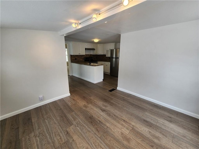 unfurnished living room with dark wood-style floors, a sink, visible vents, and baseboards