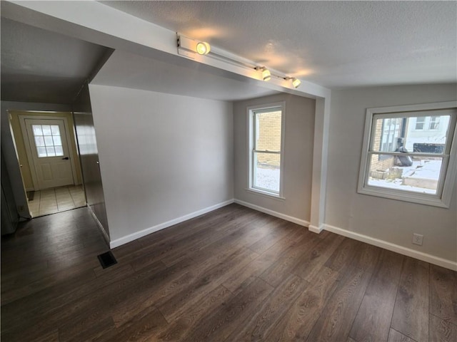 unfurnished room featuring dark wood-style floors, a textured ceiling, and baseboards