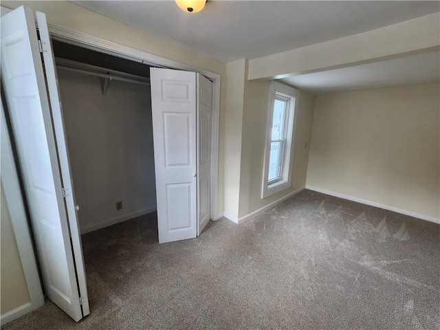 unfurnished bedroom with carpet, a closet, and baseboards