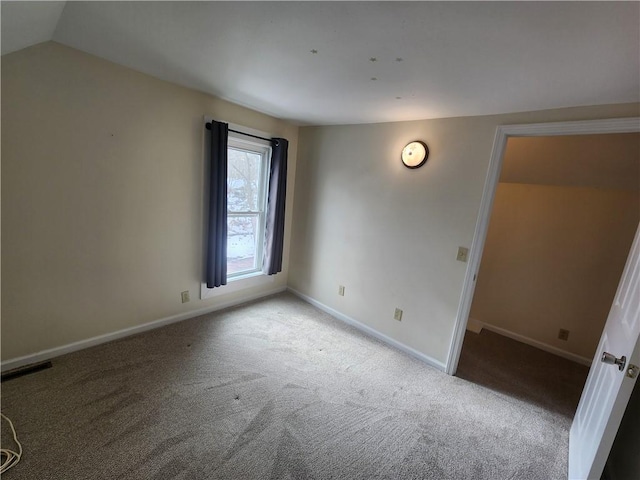 empty room with lofted ceiling, carpet, visible vents, and baseboards