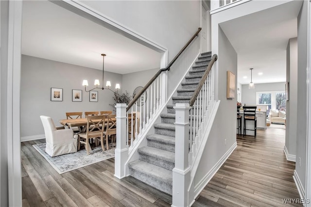 staircase with baseboards, a chandelier, wood finished floors, and recessed lighting