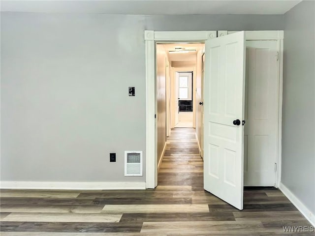 hall featuring visible vents, baseboards, and wood finished floors