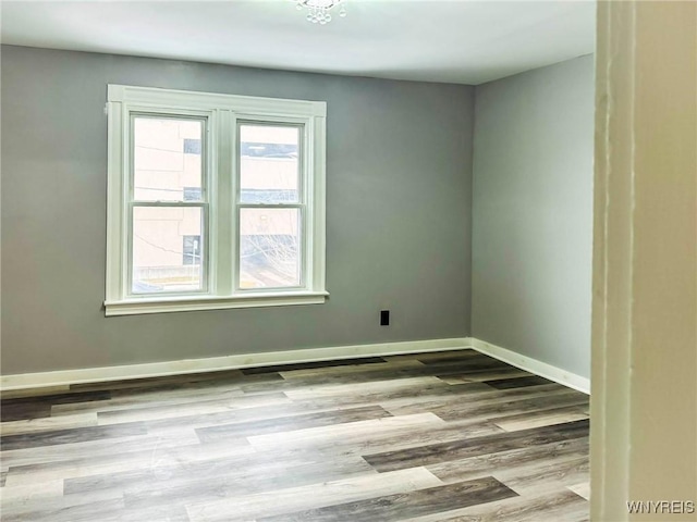 unfurnished room with baseboards and wood finished floors