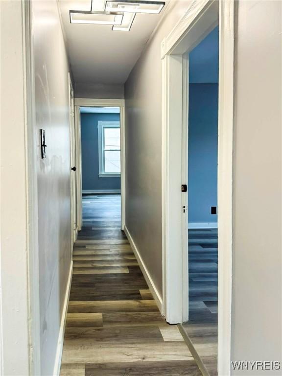 corridor featuring baseboards and wood finished floors