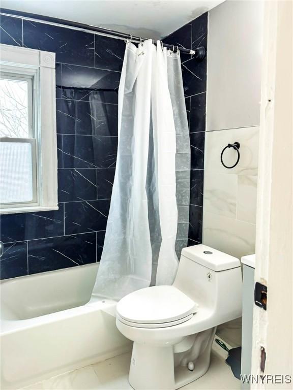 bathroom featuring toilet, shower / bath combo with shower curtain, and tile walls