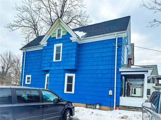 view of snow covered exterior with roof with shingles