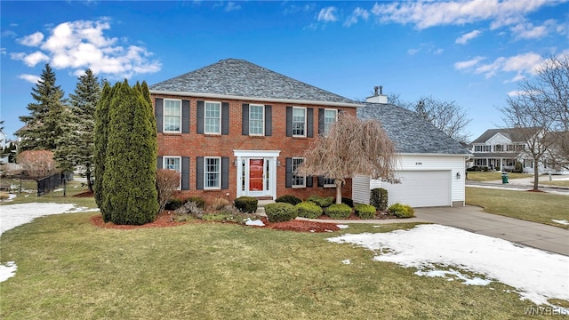 colonial home with a garage, brick siding, driveway, a front lawn, and a chimney