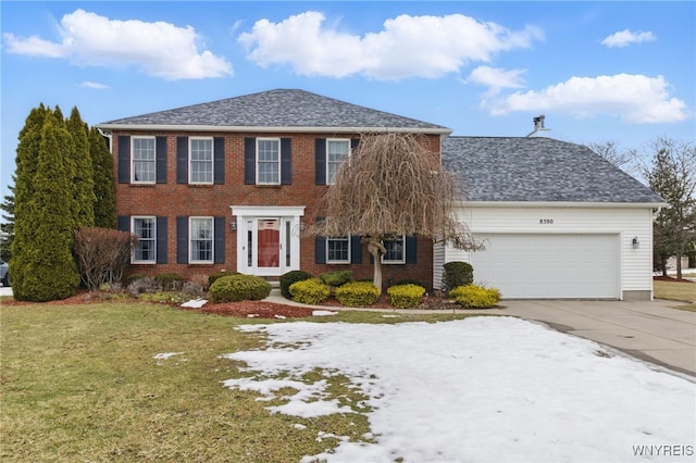 colonial inspired home featuring a garage, brick siding, a shingled roof, concrete driveway, and a front yard