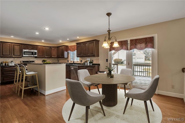 dining room with baseboards, recessed lighting, light wood-type flooring, and a notable chandelier