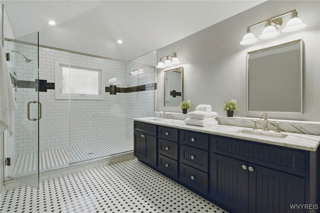 bathroom with a stall shower, a sink, and double vanity