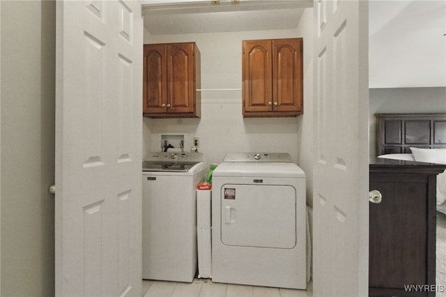 clothes washing area featuring cabinet space, light tile patterned floors, and washer and clothes dryer