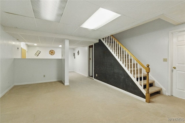 finished below grade area featuring stairs, carpet floors, a drop ceiling, and baseboards