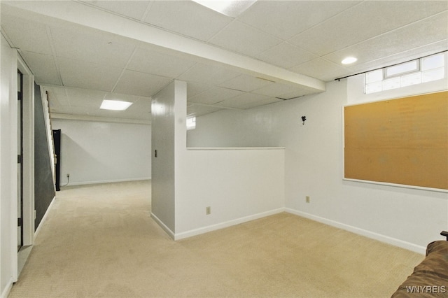 below grade area with carpet floors, a paneled ceiling, and baseboards