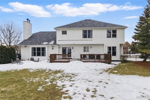 snow covered property with a chimney and a deck