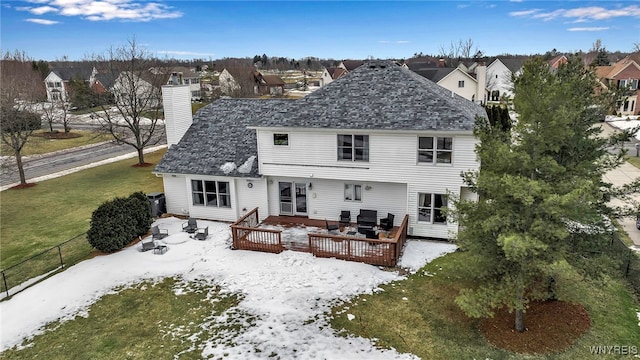 back of property featuring a shingled roof, a residential view, a chimney, a yard, and a wooden deck